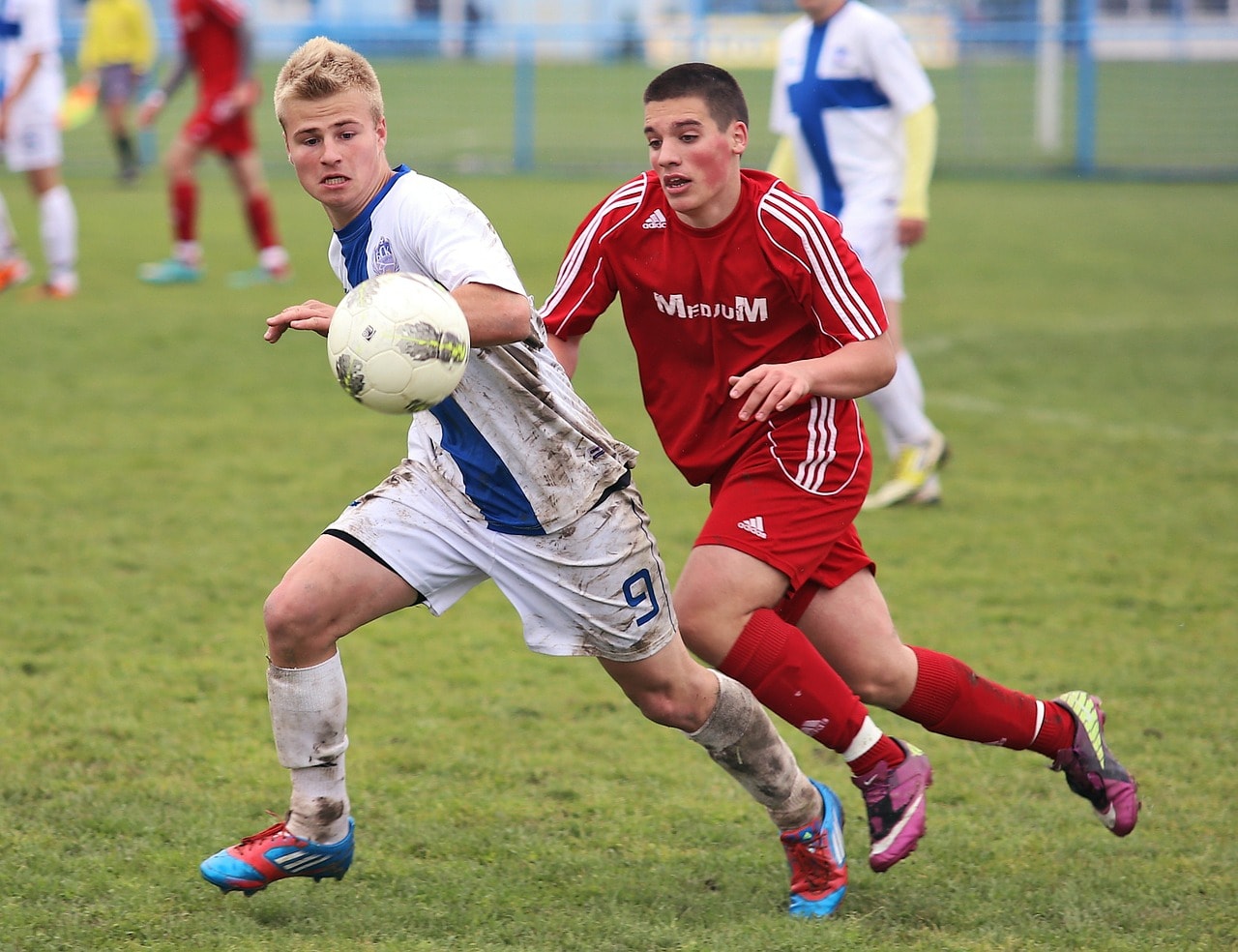 Two soccer players chasing the ball.