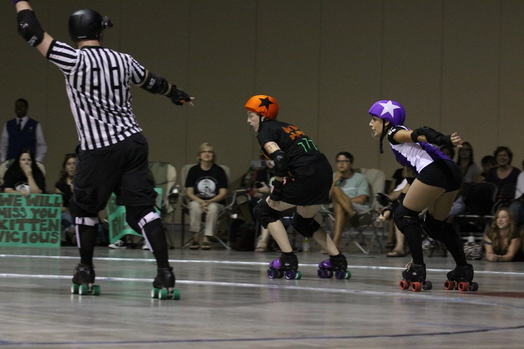 Two roller derby jammers taking a corner.